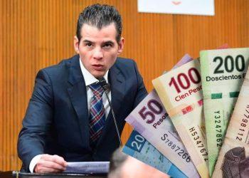 Man in a Suit Speaks into a Microphone at a Podium, with Colorful Banknotes Fanned to the Right, Suggesting Money or Bribery. - Tu Colonia Regia