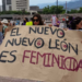 Protesters Hold a Large Handwritten Banner That Reads 'el Nuevo León Es Feminicida' at a Demonstration, with People and Buildings in the Background. - Tu Colonia Regia